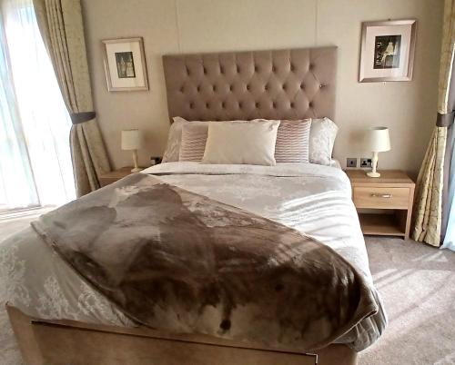 a bedroom with a large bed and two night stands at Luxury Lodge at Southview - perfect for couples with pond view and sun room in Skegness