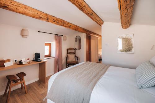 a bedroom with a white bed and a desk at Les Terrasses de la Borie in Mandagout