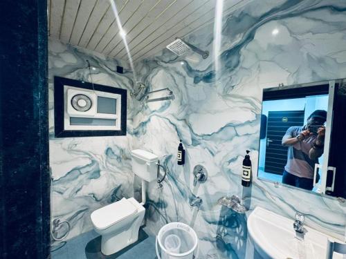 a man taking a picture of a bathroom with a marble wall at Hotel Green Valley in Raipur