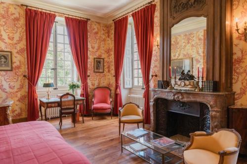 a bedroom with a fireplace and red curtains at Château-Hôtel de Bourron in Bourron-Marlotte