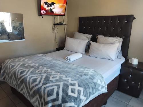 a bed with a black headboard and white pillows at Sun & Night in Empangeni