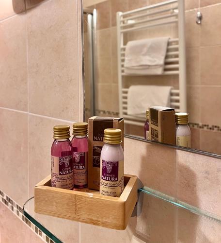a shelf with four bottles of hair products in front of a mirror at Betty's House in Lazise