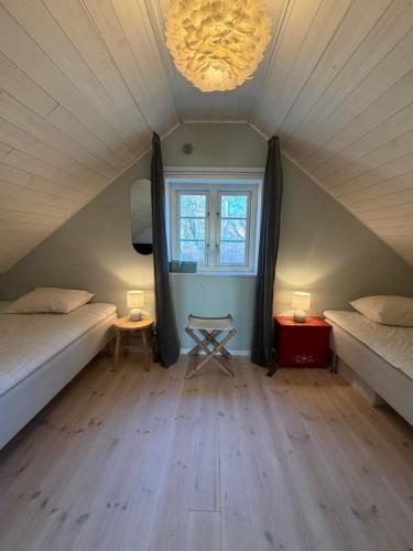 a attic room with two beds and a window at Idyllically nice house on Bjärehalvön, Torekov! in Båstad