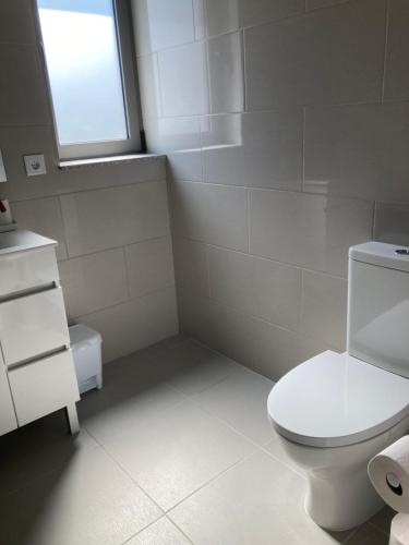 a bathroom with a white toilet and a window at Casa Alex in Arão
