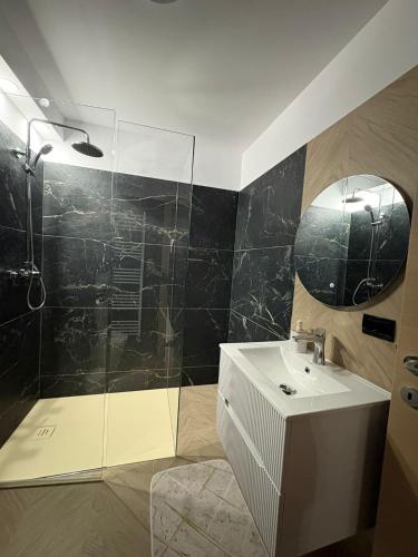 a bathroom with a shower and a sink and a mirror at Borșa ApartHotel 5 in Borşa