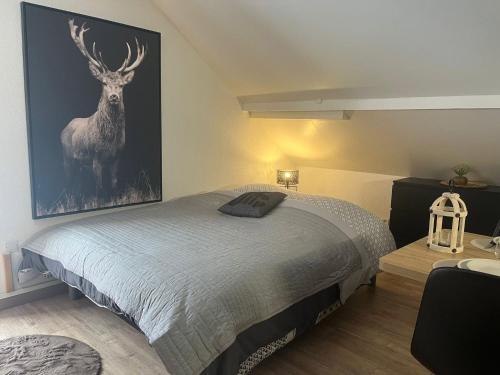 a bedroom with a bed with a painting of a deer at Studio Chalet des Pistes in Gérardmer