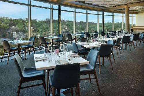 a dining room with tables and chairs and windows at The Fontaine in Kansas City