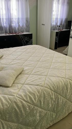 a large white bed in a room with windows at Bodini Mountain House in Peqin