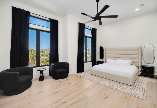 a white bedroom with a bed and two chairs at Isle Be Back in Destin