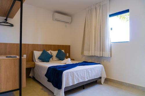 a bedroom with a bed with blue pillows and a window at Bananeiras Solar in Bananeiras