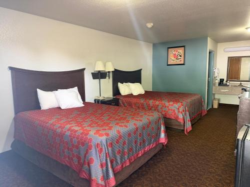 a hotel room with two beds with red sheets at The Magnolia Hotel Searcy in Searcy