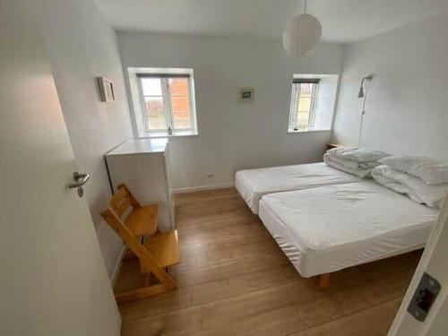 a white room with a bed and two windows at 20334-Samso-Kaerbakken-13 in Hårdmark