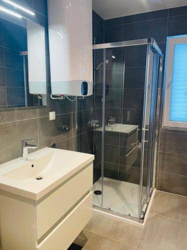 a bathroom with a sink and a glass shower at Apartmani Villa Antea in Klek