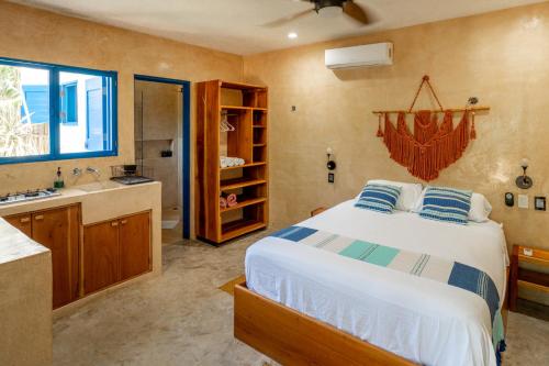 a bedroom with a bed and a bathroom with a sink at Casa Omero Garden in El Cuyo