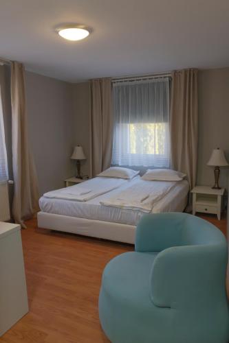 a bedroom with a large bed and a blue chair at Aleu - Apuseni Mountains in Pietroasa