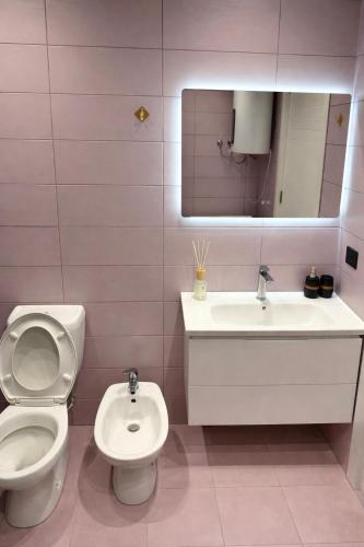 a pink bathroom with a toilet and a sink at FIN Skyline Apartment in Krujë