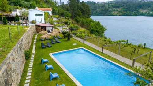 a swimming pool with chairs and umbrellas next to a lake at Quinta do Regato Douro in Penafiel