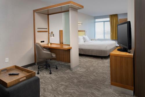 a hotel room with a bed and a desk with a television at SpringHill Suites Potomac Mills Woodbridge in Woodbridge