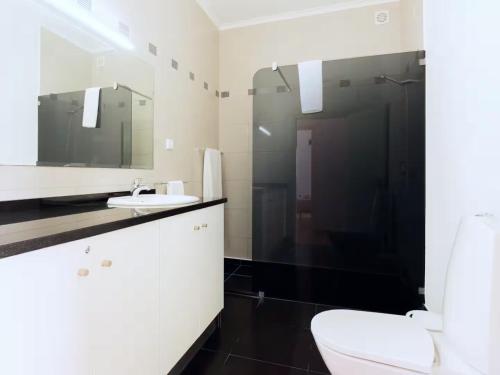 a bathroom with a toilet and a sink and a mirror at Skyline Villas RC in Arco da Calheta