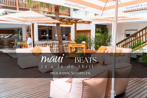 a restaurant with tables and umbrellas on a deck at Hotel Maui Maresias in Maresias