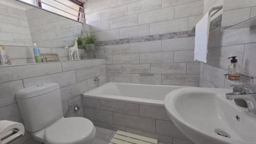 a bathroom with a toilet and a tub and a sink at Beach Bliss Retreat in Margate