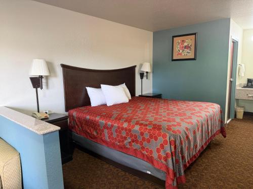 a hotel room with a bed with a red bedspread at The Magnolia Hotel Searcy in Searcy
