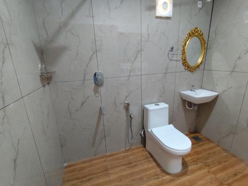 a bathroom with a toilet and a sink and a mirror at Spice Garden Clove Villa in Batheri