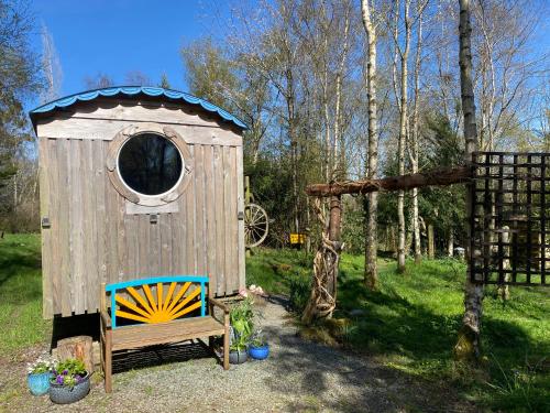 a wooden out house with a bench in a yard at Sapphire forest garden shepherd’s hut in Church Stretton