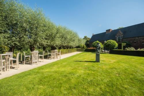a lawn with chairs and tables in a garden at Begijnhof Hotel in Leuven