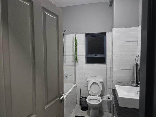 a white bathroom with a toilet and a sink at Sky Apartment Mbabane CBD in Mbabane