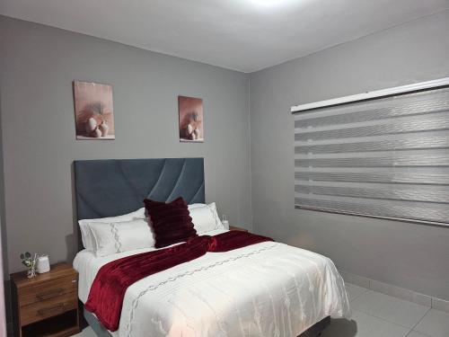 a bedroom with a white bed and a window at Sky Apartment Mbabane CBD in Mbabane