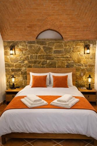 a bedroom with a large bed with a stone wall at O Cantinho dos Avós in Mourão