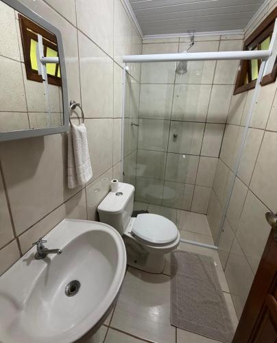 a white bathroom with a sink and a toilet at Hotel empresarial HARRY WORLD in Curitibanos