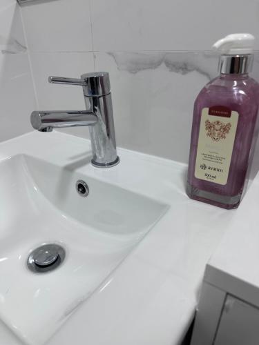 a bottle of soap sitting on top of a bathroom sink at Rooms Moscavide quartos in Lisbon