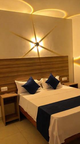 a bedroom with a large bed with blue pillows at Kimbar Suites in Mombasa