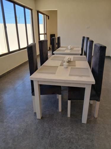 a dining room with a table and chairs and windows at Kimbar Suites in Mombasa
