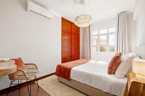 a bedroom with a bed and a chair and a window at Villa Vineyard by Homie in Câmara de Lobos