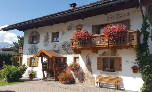 a building with flowers on the balcony and a bench at Ferienwohnung ZUGSPITZE in Krün