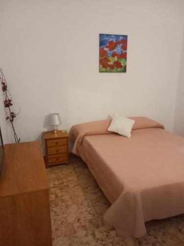 a bedroom with a bed and a table with a picture on the wall at Habitaciones turísticas copitos in Gandía