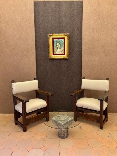 two chairs and a table with a picture on a wall at Avicena Hotel Boutique in Cuernavaca