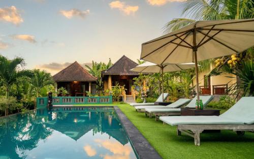 an image of a resort pool with lounge chairs and an umbrella at Bali Nusa Cottage in Nusa Lembongan