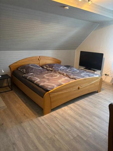 a bedroom with a large bed with a flat screen tv at Gästezimmer Polster in Birstein