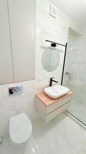 a white bathroom with a toilet and a sink at TRIO Sun Class Park Residence in Târgovişte