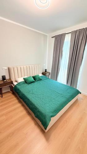 a bedroom with a large bed with a green blanket at TRIO Sun Class Park Residence in Târgovişte