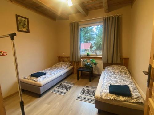 two beds in a room with a window at DOM NA WYŁĄCZNOŚĆ- Odpoczynek w sercu Mazur in Miłki