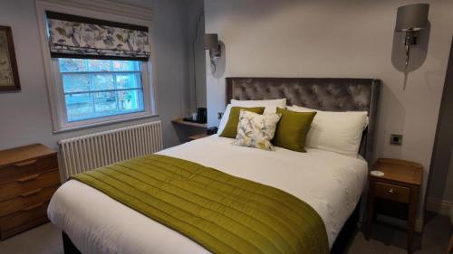 a bedroom with a large bed with a green blanket at The Gregory Arms in Harlaxton