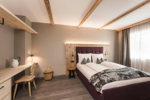 a bedroom with a large bed and a desk at TANOVINUM Apartments in Villandro