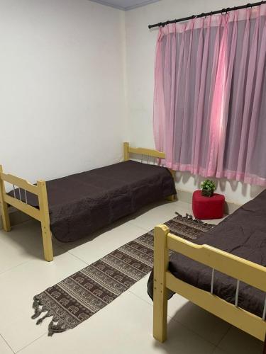 a bedroom with two beds and a pink curtain at Recanto Chaparral in Aragoiânia