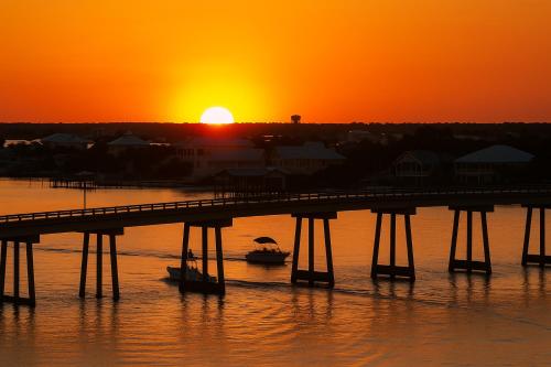 a bridge over the water with a sunset in the background at Wind Drift North 211-NEW-Bayfront-Beach access-Boat Slips-Sleeps 8 in Orange Beach