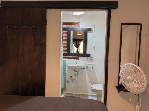 a bathroom with a toilet and a mirror and a fan at Casa OMI in Brisas de Zicatela